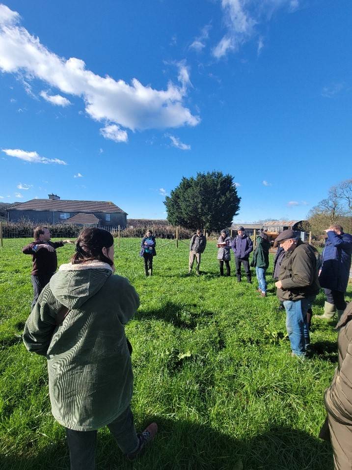 Visite de terrain pour les membres du réseau ATTER, le groupe est dans un champ et écoute un homme qui parle